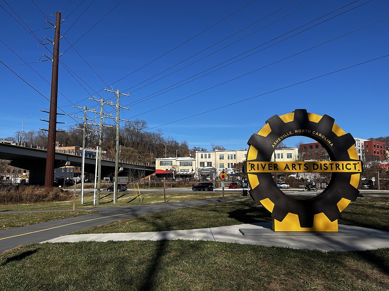 The gear-shaped River Arts District sign beside a road in Asheville.