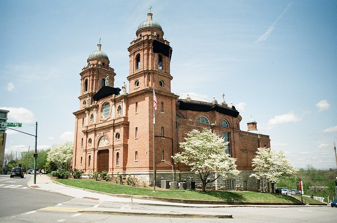The Basilica of St. Lawrence on its corner lot, framed by flowering dogwoods.