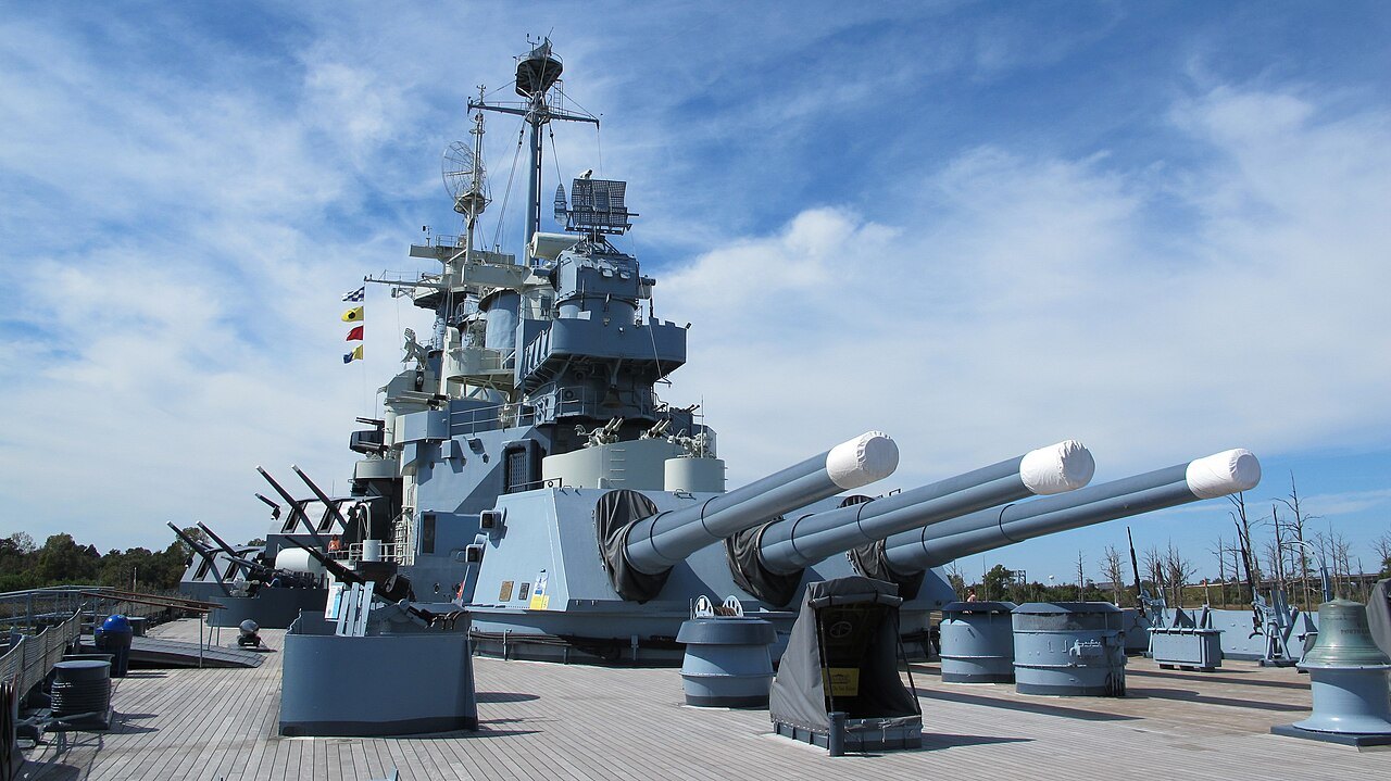 The bridge tower and a turret of the battleship against a clear sky.