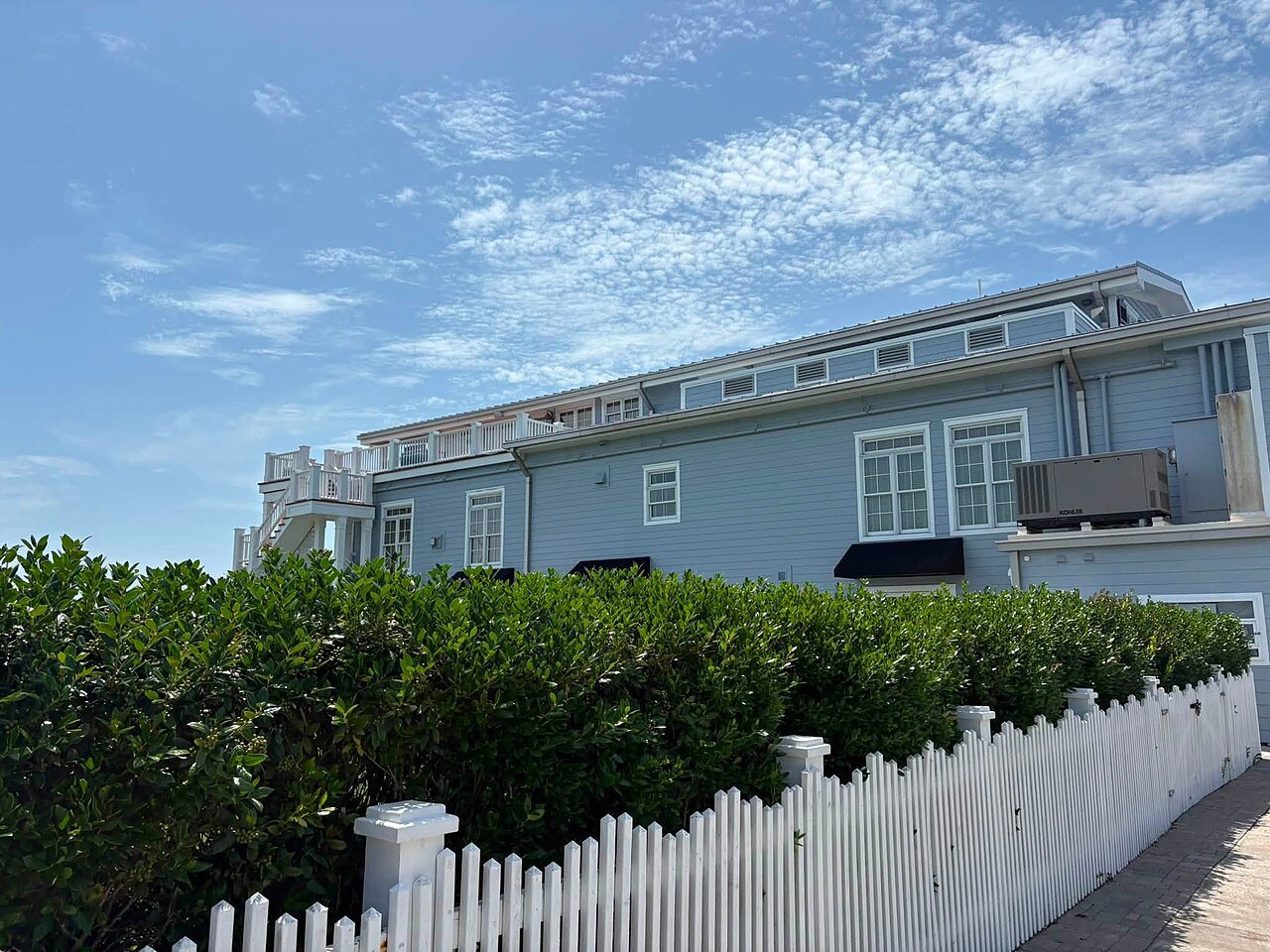 A blue-grey building behind a white picket fence in downtown Beaufort.