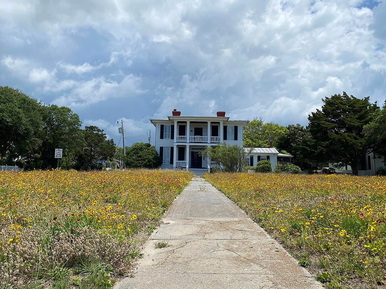 A path through wildflowers to a two-story house with porches in Beaufort.