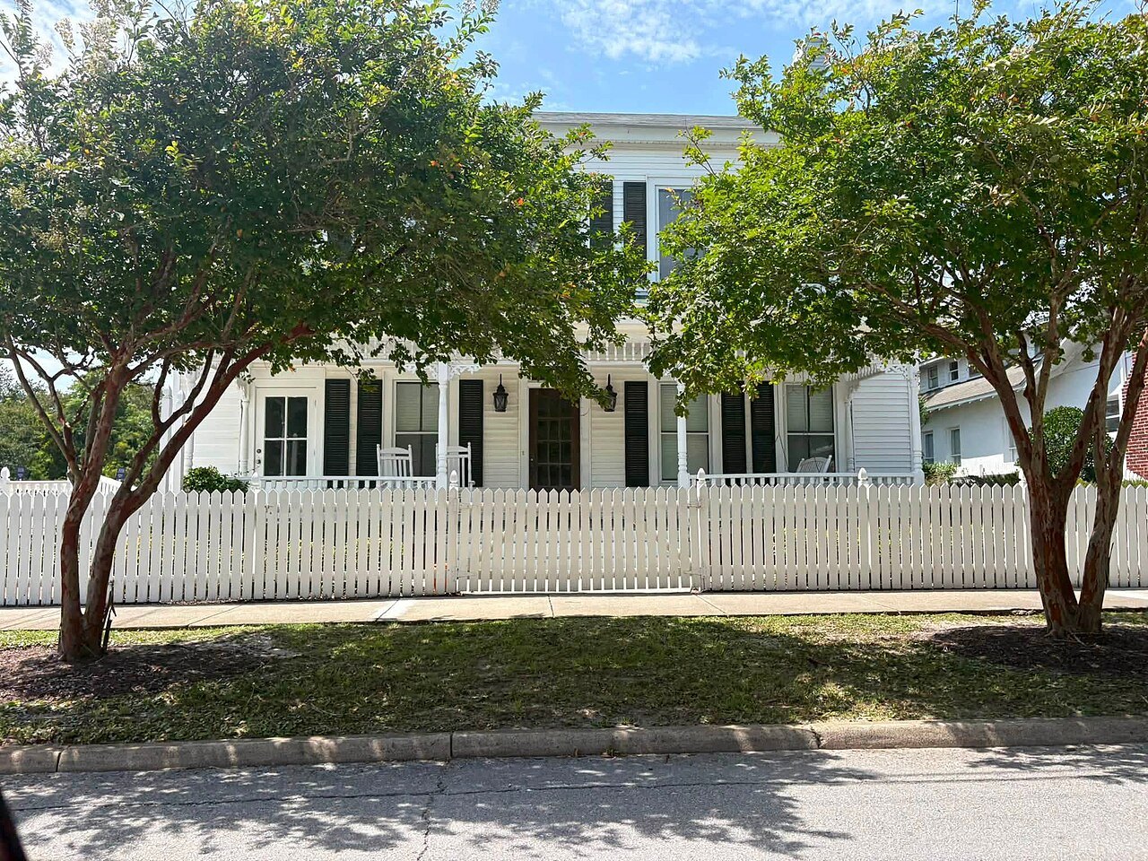 A large white house behind a picket fence and crape myrtles in Beaufort.