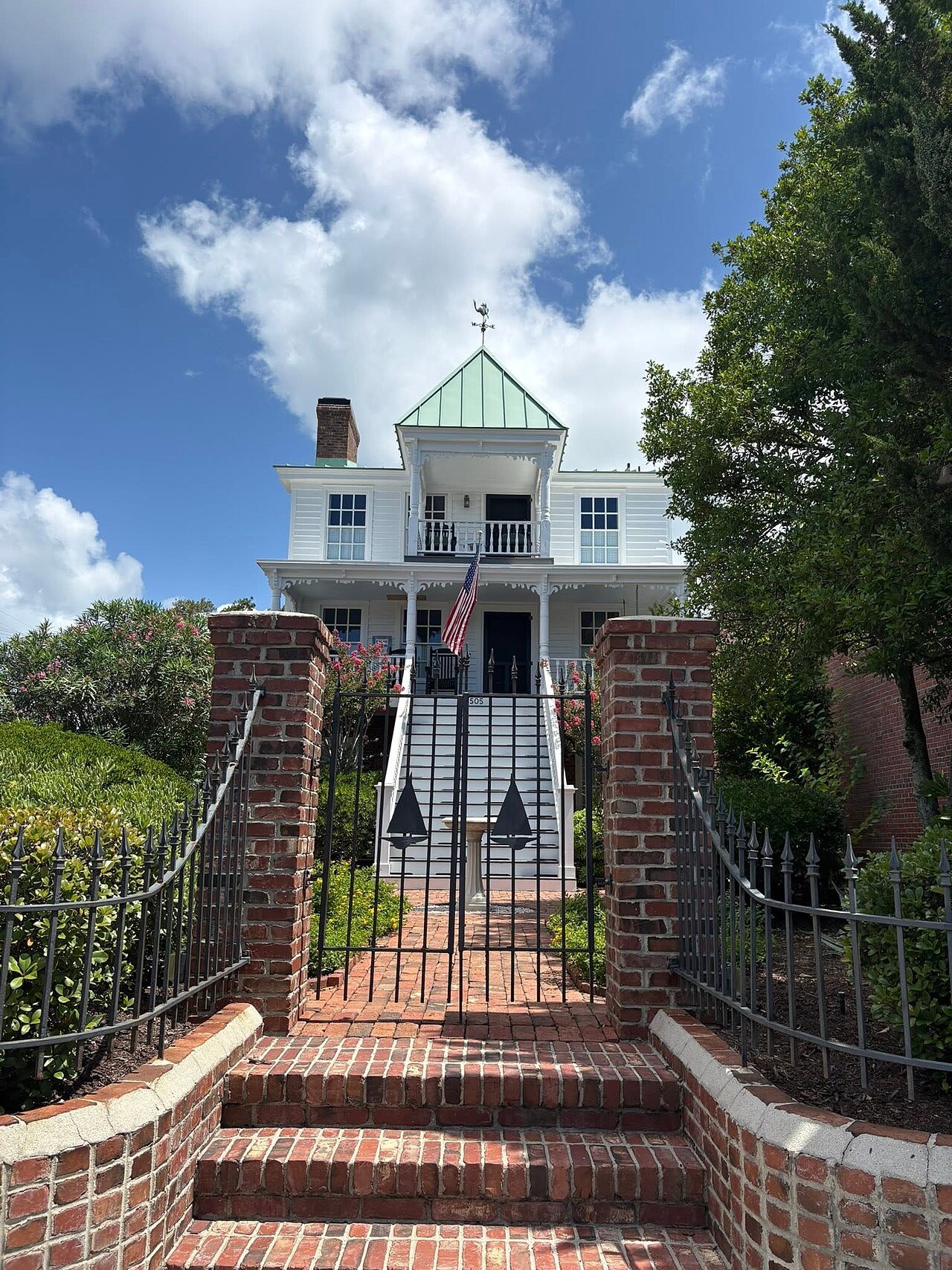 Brick gateposts and steps up to a white house with a cupola in Beaufort.