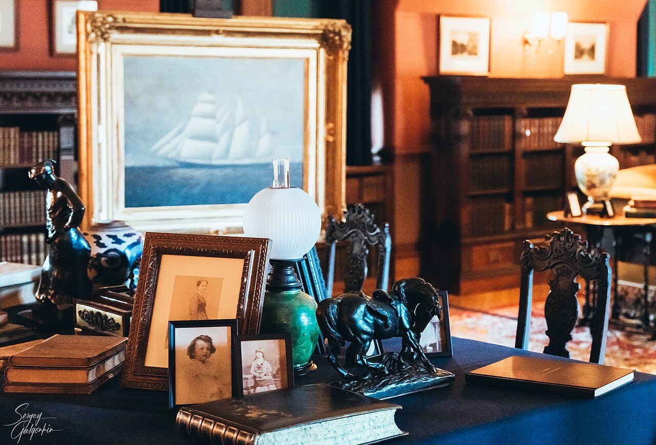 A desk with photographs and a ship painting in a room of Biltmore House.