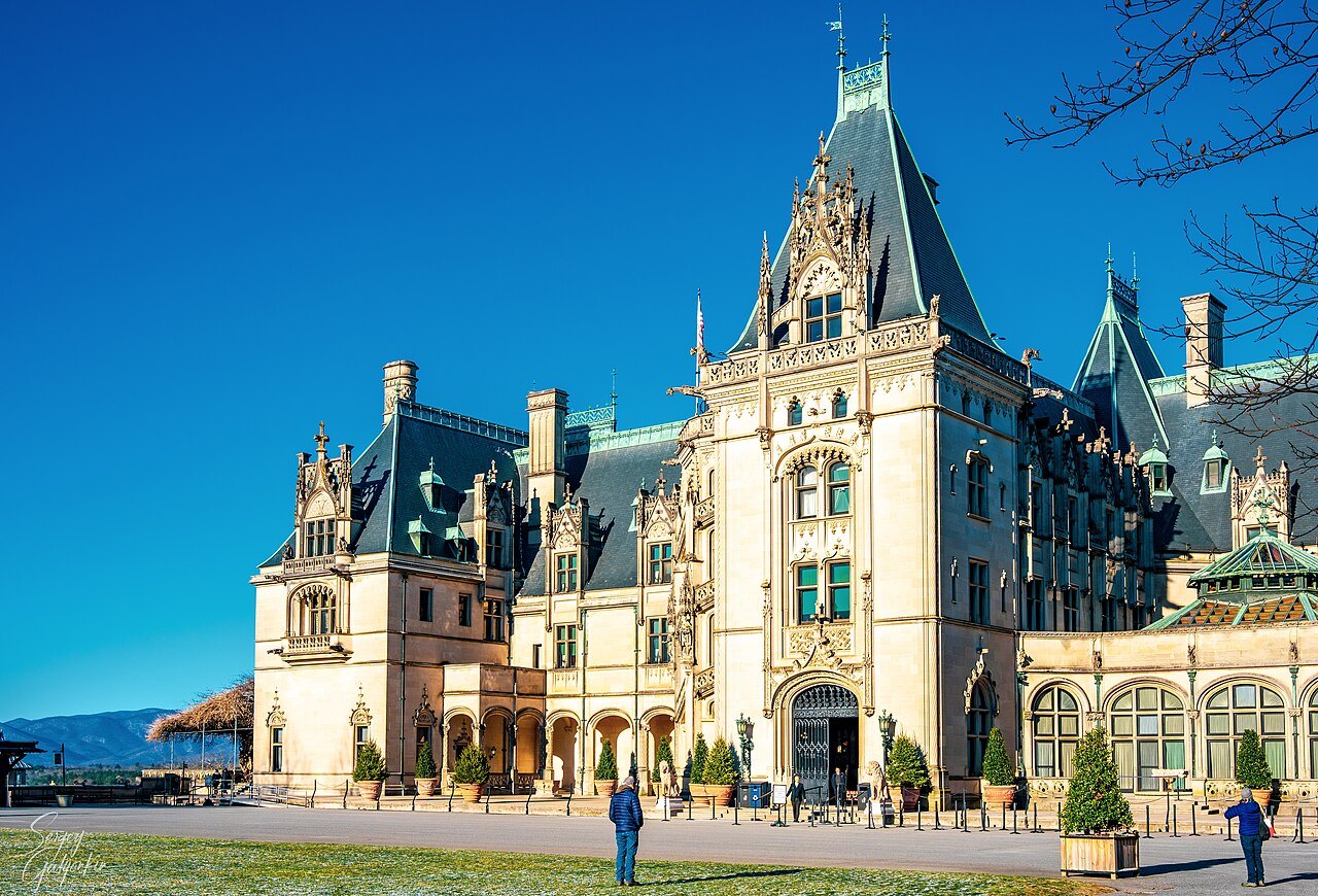 The limestone front of Biltmore House under a deep blue sky.