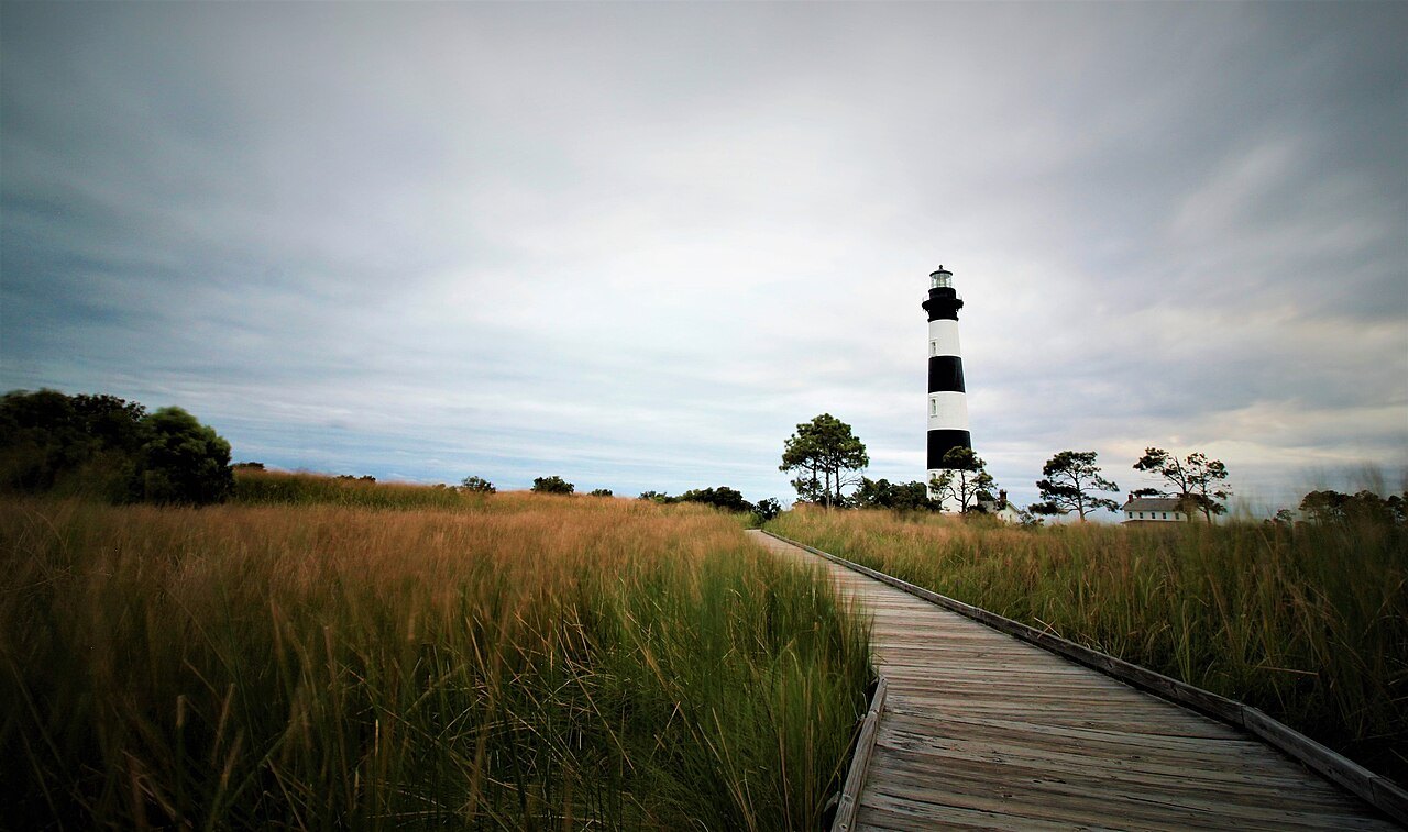A boardwalk through marsh grass toward the Bodie Island Lighthouse.