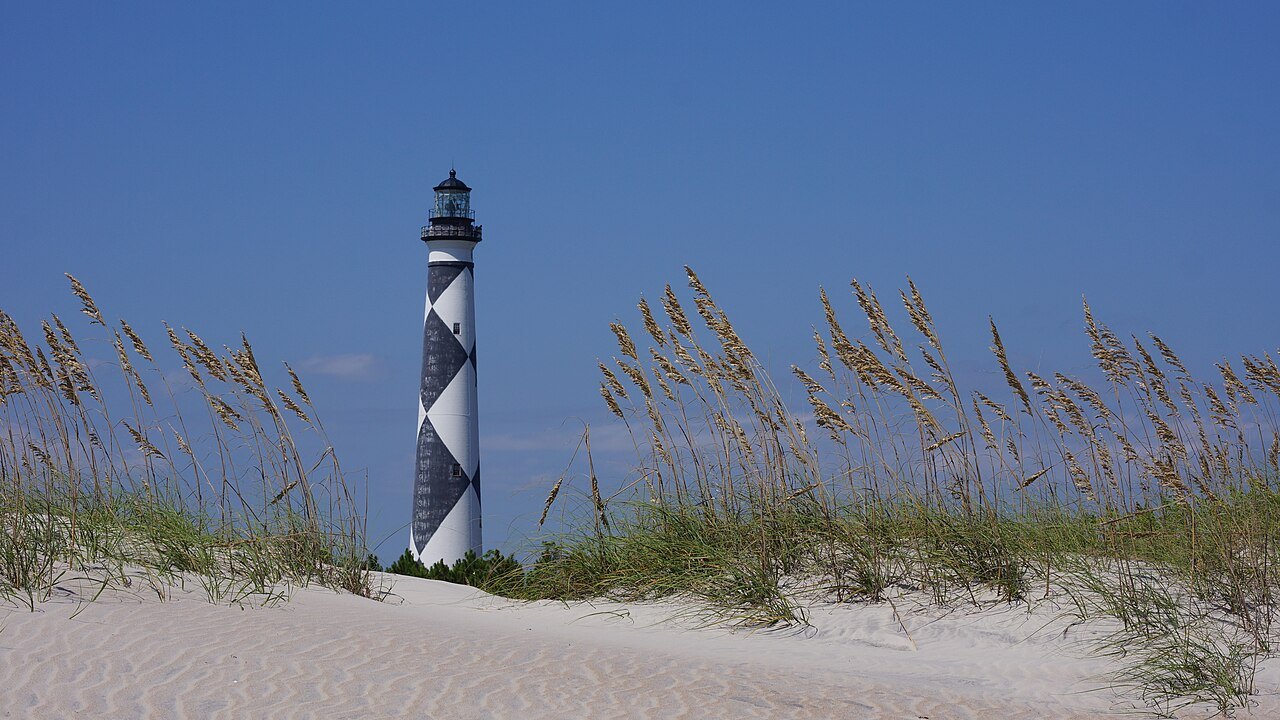 The Cape Lookout Lighthouse behind sea oats on a dune.