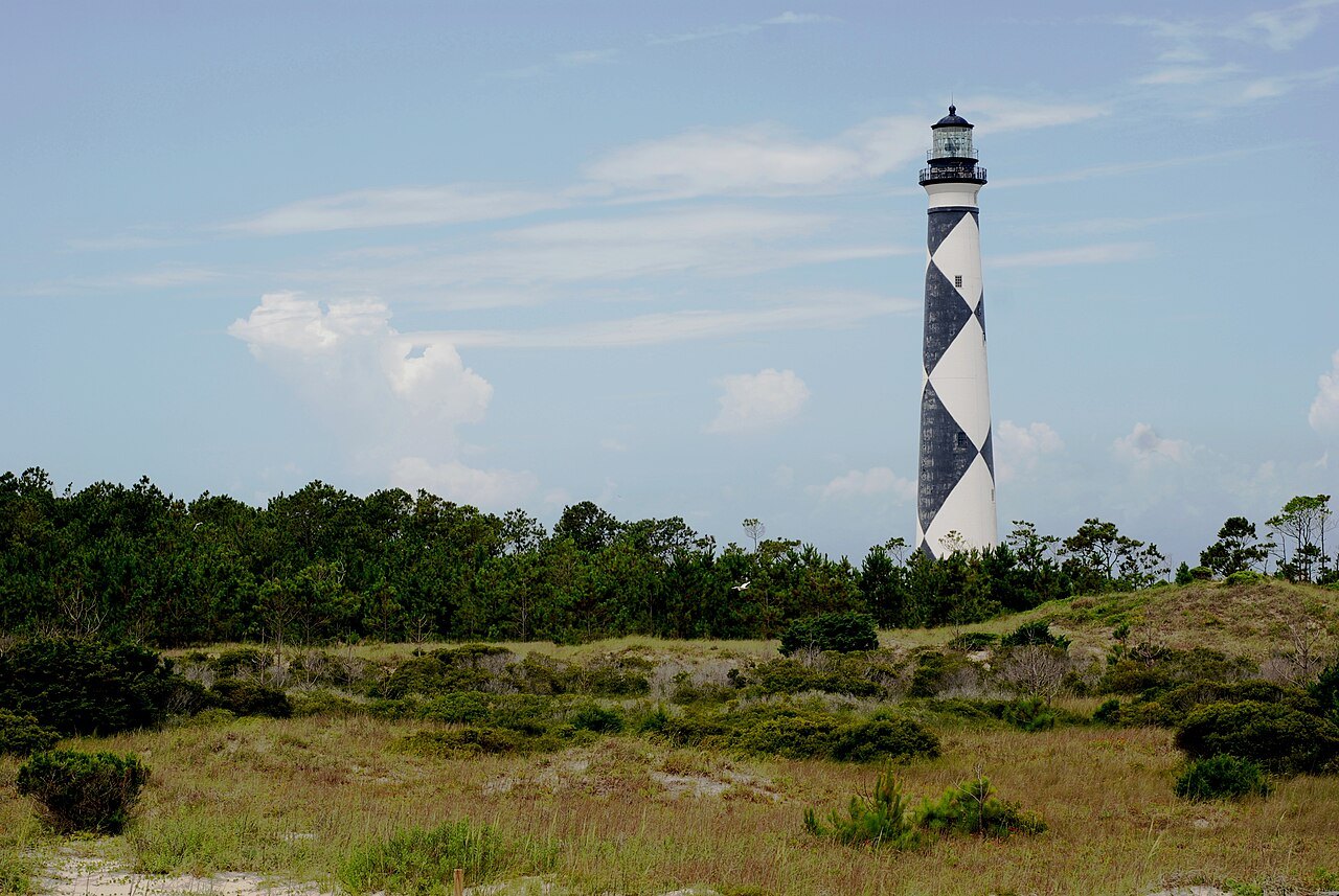 The diamond-patterned Cape Lookout Lighthouse above the dune scrub.