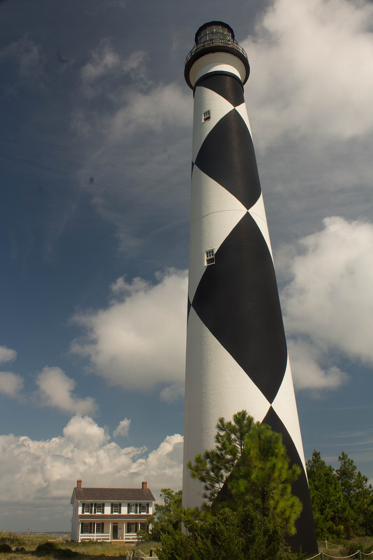 The checkered lighthouse tower and the keepers' house under a stormy sky.