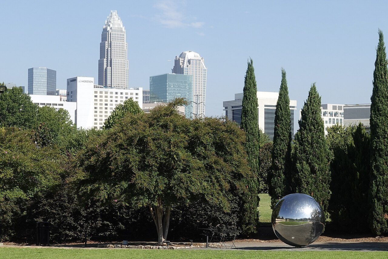 Uptown Charlotte's towers above the trees and a steel sphere in Midtown Park.