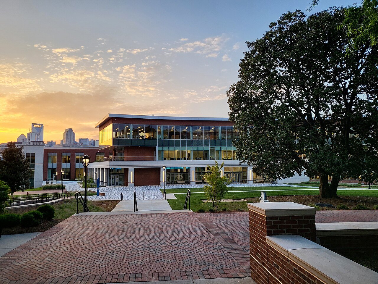 A brick-and-glass building behind a plaza at sunset in Charlotte.