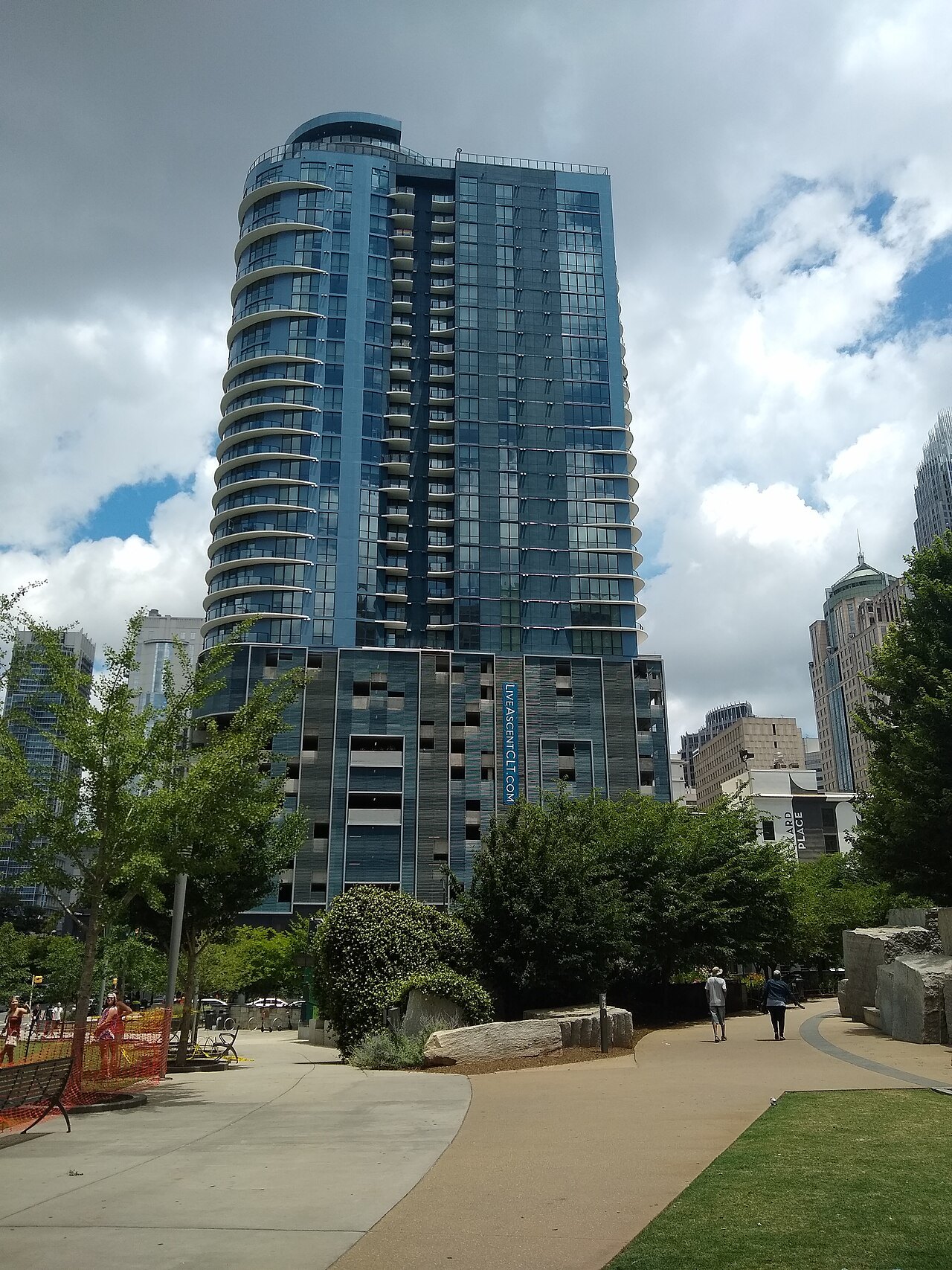A glass residential tower above a landscaped walk in Uptown Charlotte.