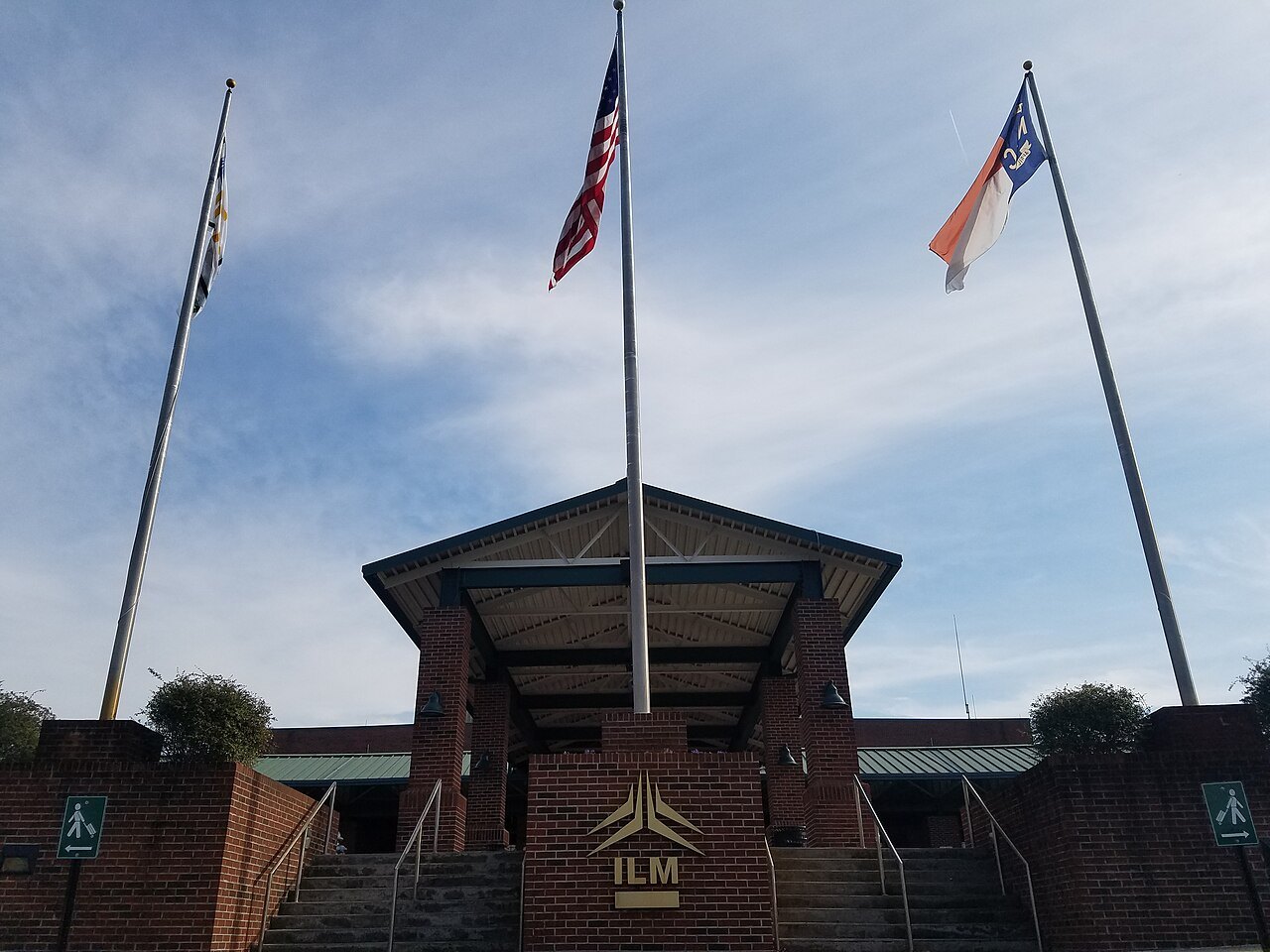 The main terminal entrance of Wilmington International Airport under three flags.