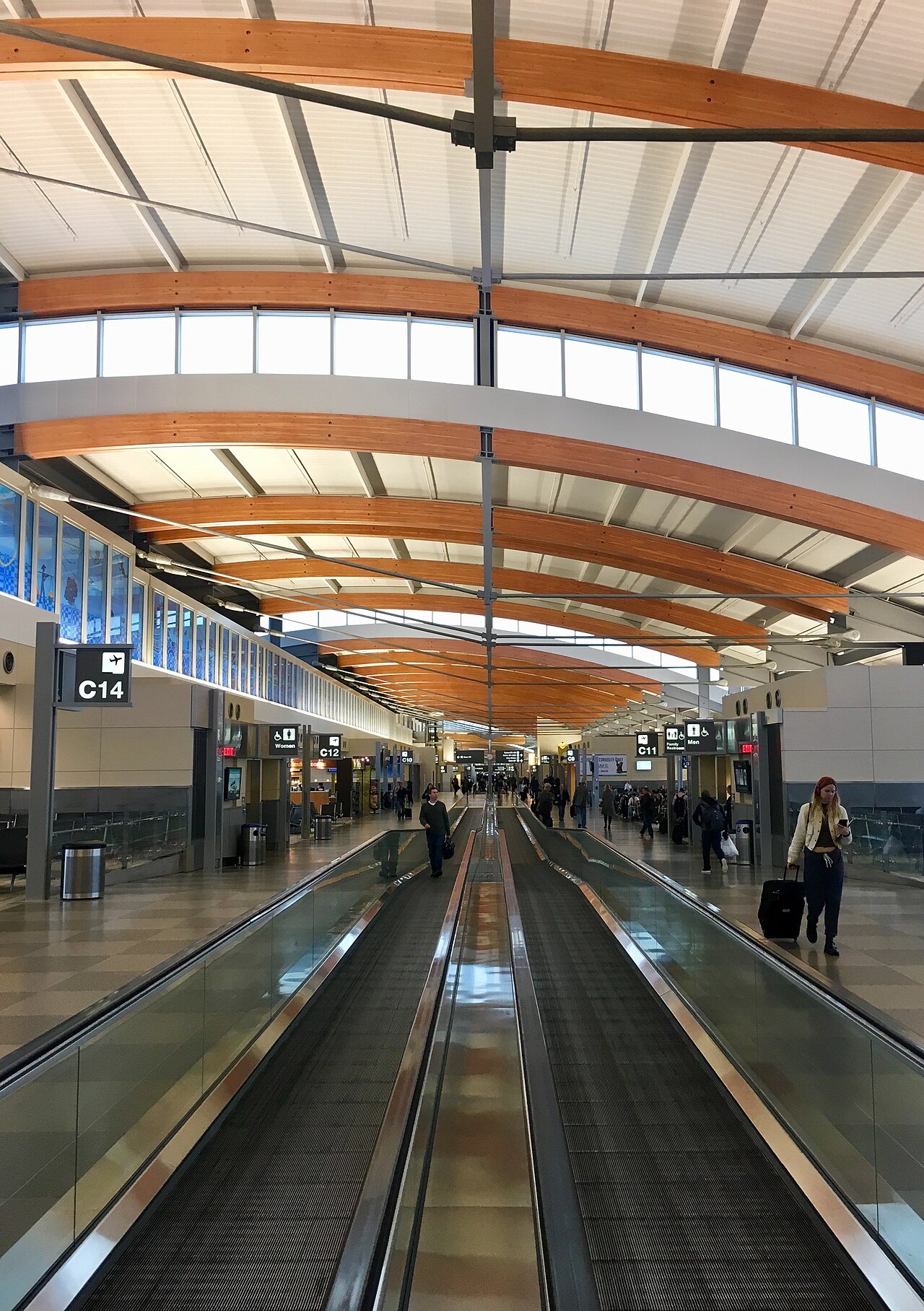 Travelers on a moving walkway in an RDU concourse.