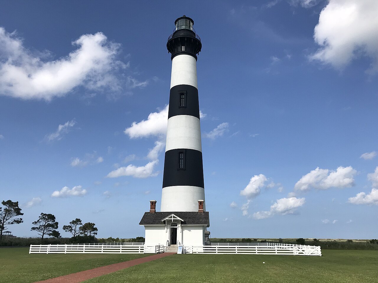 The Bodie Island Lighthouse and keepers' house under summer clouds.