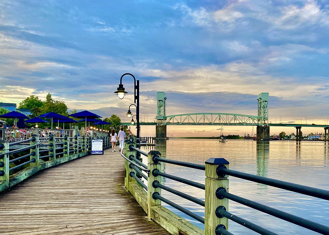 The Wilmington Riverwalk at sunset, with the Cape Fear Memorial Bridge beyond.