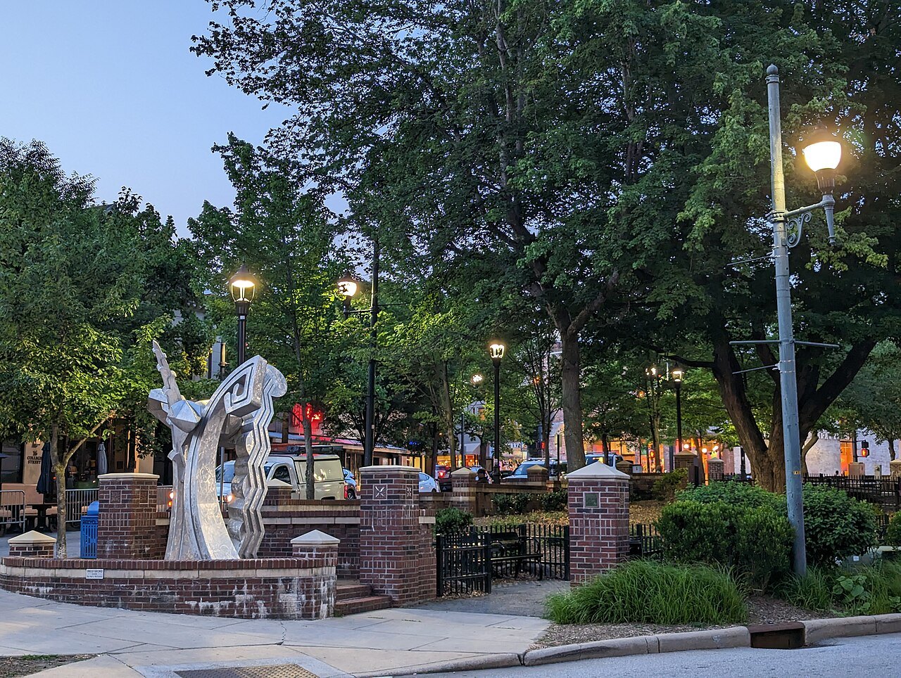 A sculpture and trees in a small plaza on a summer evening in Asheville.