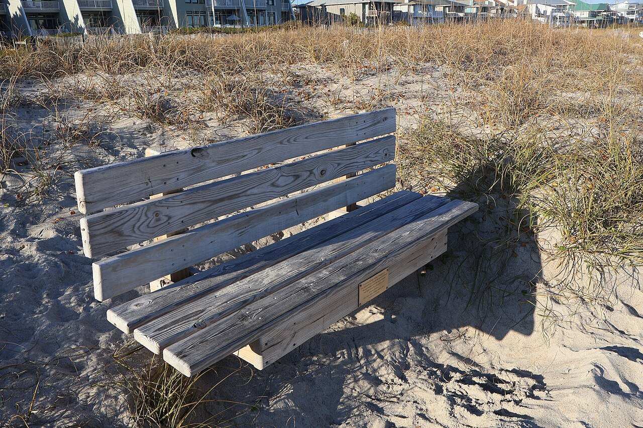 A weathered bench on the dunes by the beach.