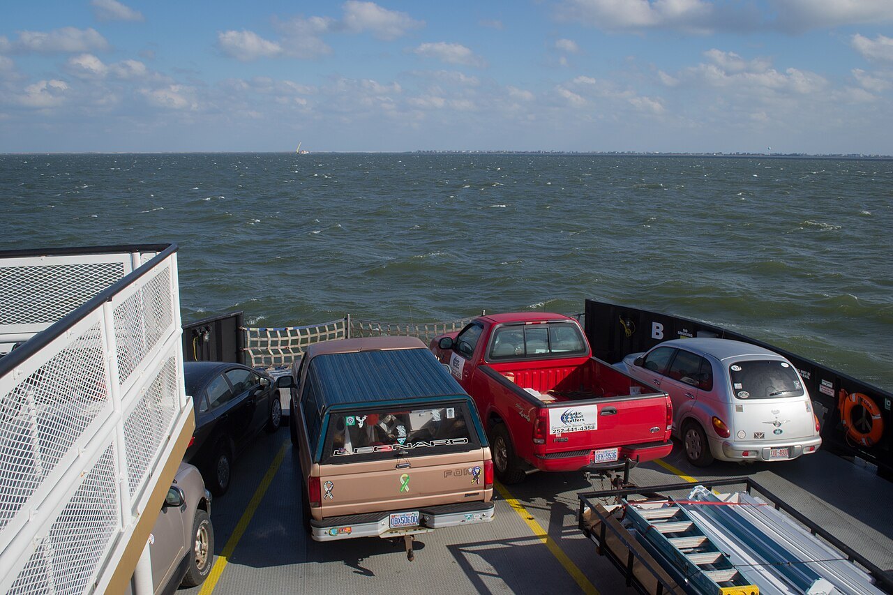 Cars and a pickup lined up on the open deck of a state ferry.