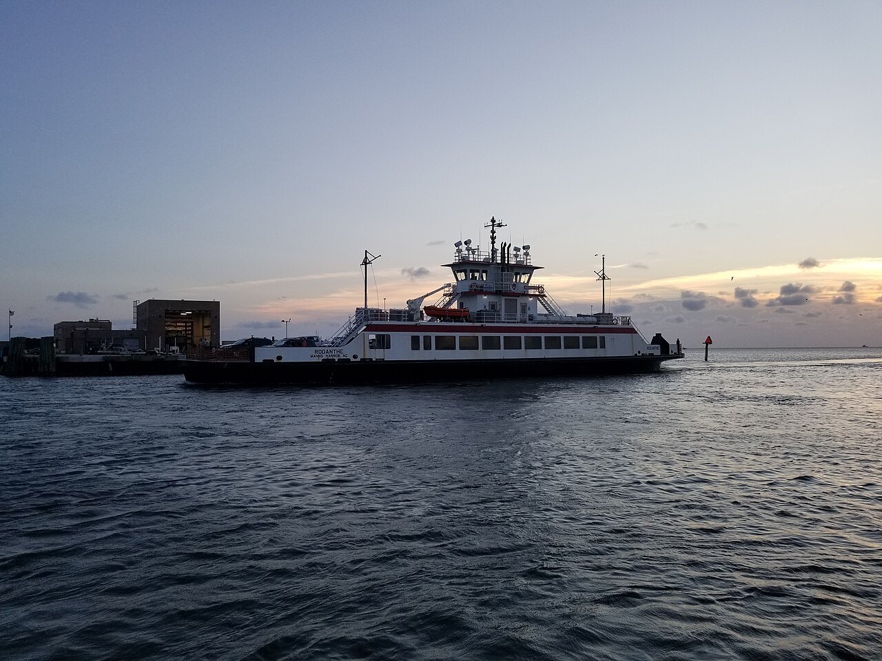 A state ferry crossing toward the dock in the evening light.