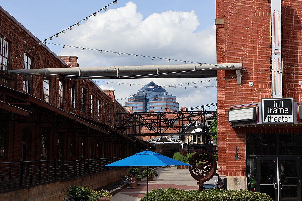 Café umbrellas and string lights between the brick buildings of downtown Durham.
