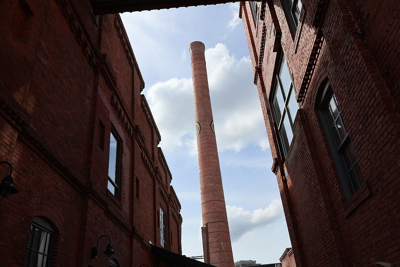 The brick smokestack of the old Lucky Strike factory between warehouse walls.