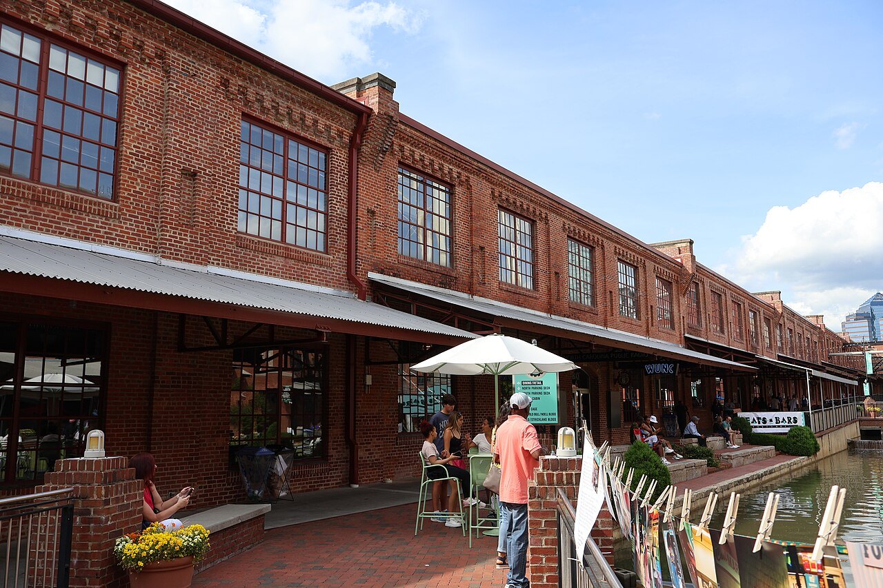 Outdoor tables beside the brick warehouses of the American Tobacco Campus in Durham.