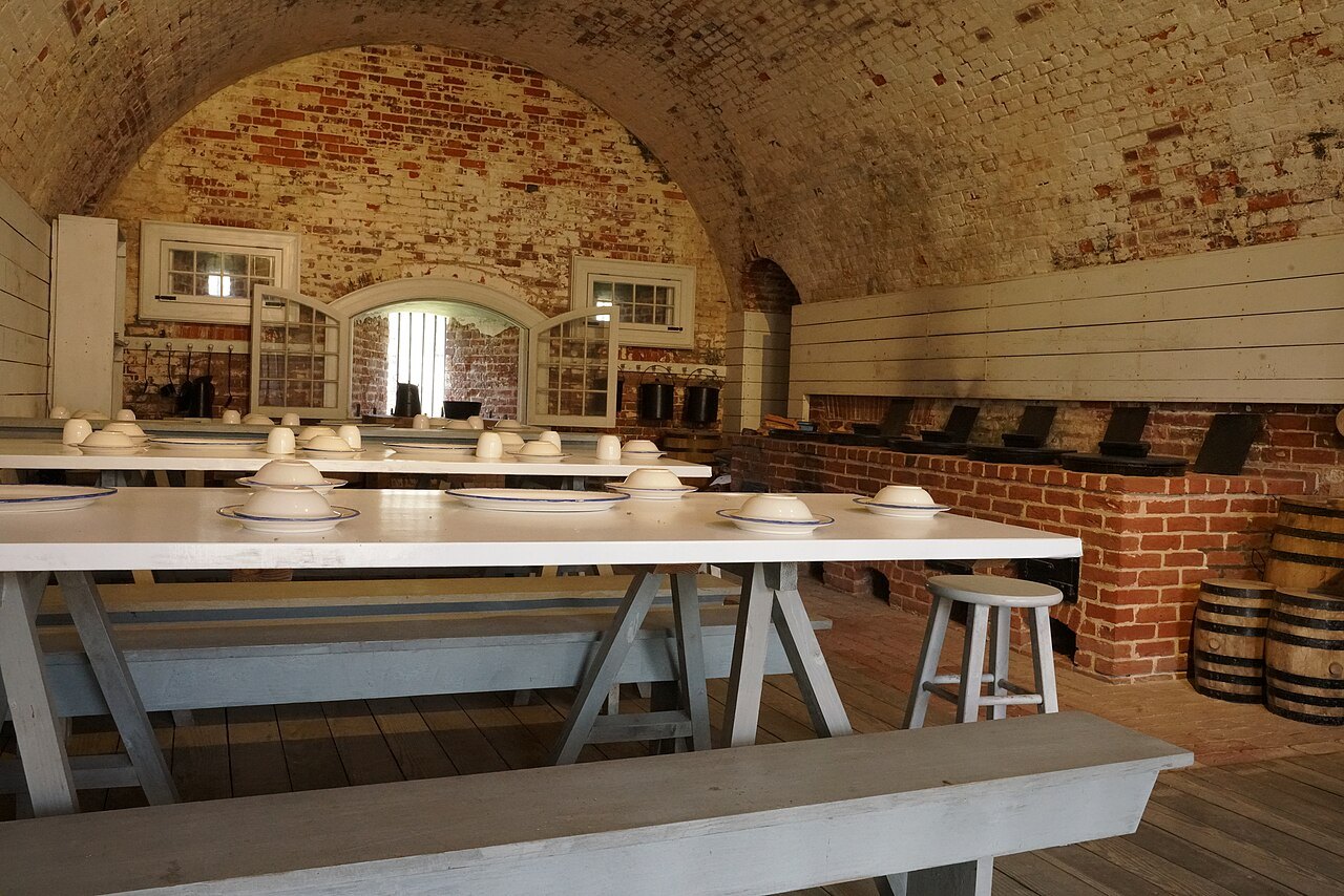 A casemate set out as a mess hall, with long tables under the brick vault.