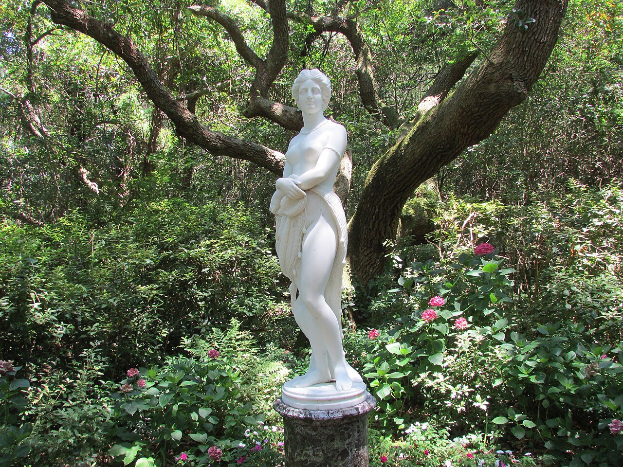 A marble statue of Virginia Dare under a live oak in the Elizabethan Gardens.