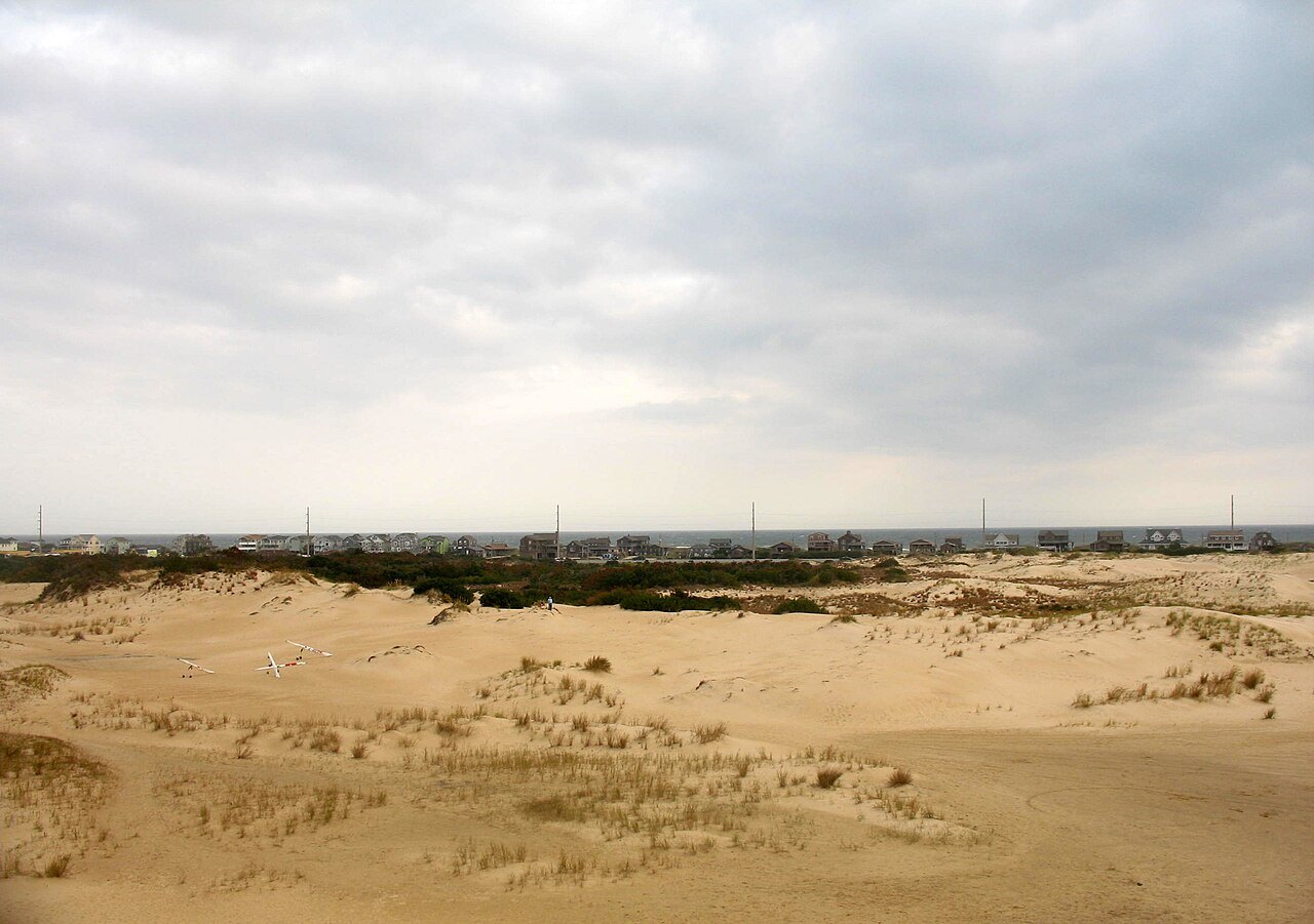 Low dunes and scrub at Jockey's Ridge under a grey sky.