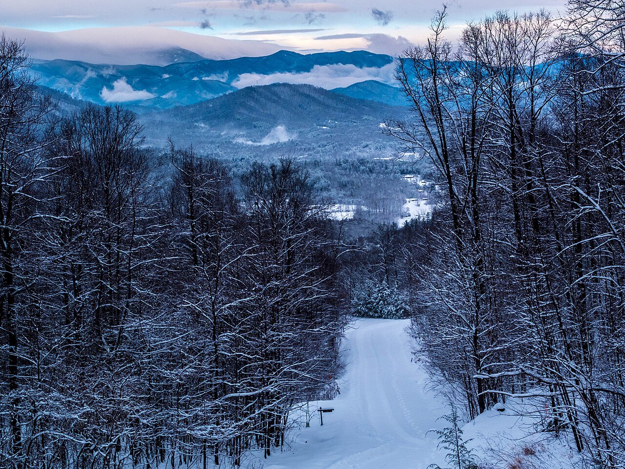 Snow on the trees and a road below Mount Mitchell, with the ranges beyond.
