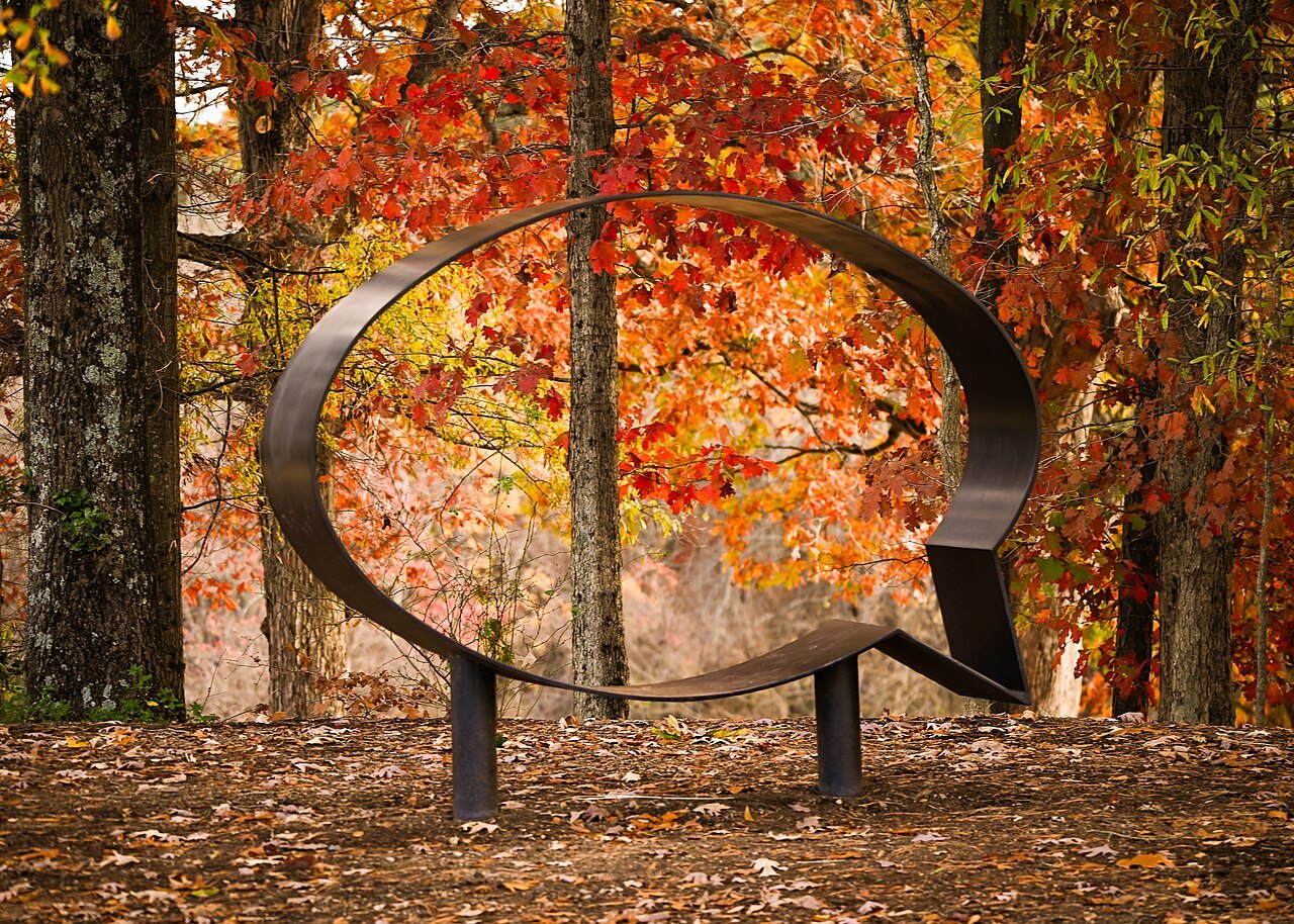 A steel speech-bubble bench against autumn leaves in the Museum Park.