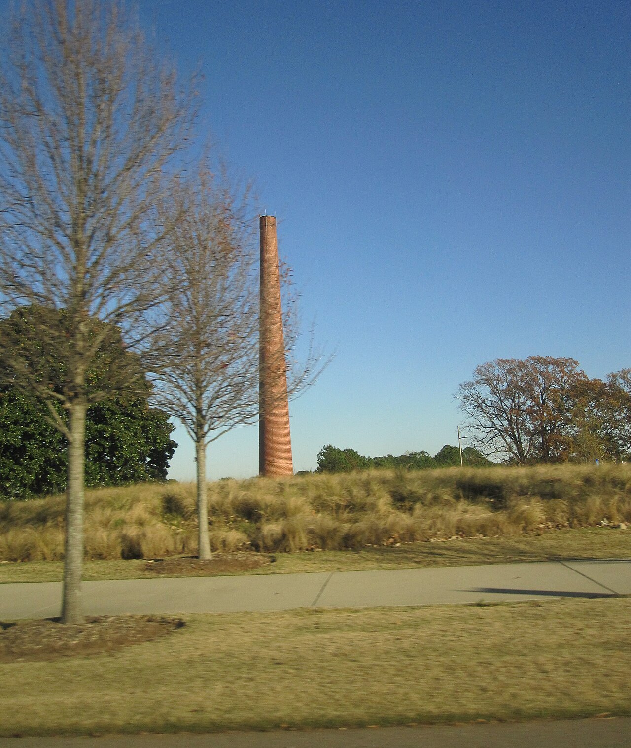 A tall brick smokestack standing in the grounds of the North Carolina Museum of Art's park.