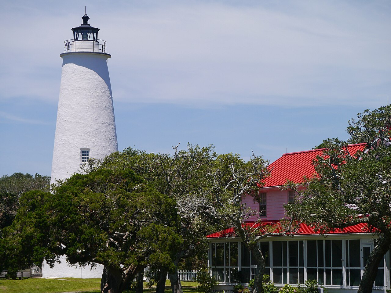 The Ocracoke Light above the trees and a red-roofed house in the village.
