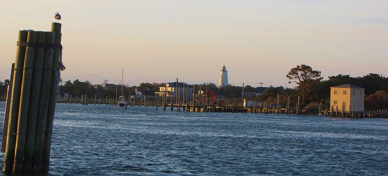 Silver Lake harbor at dusk, with the Ocracoke Light beyond.