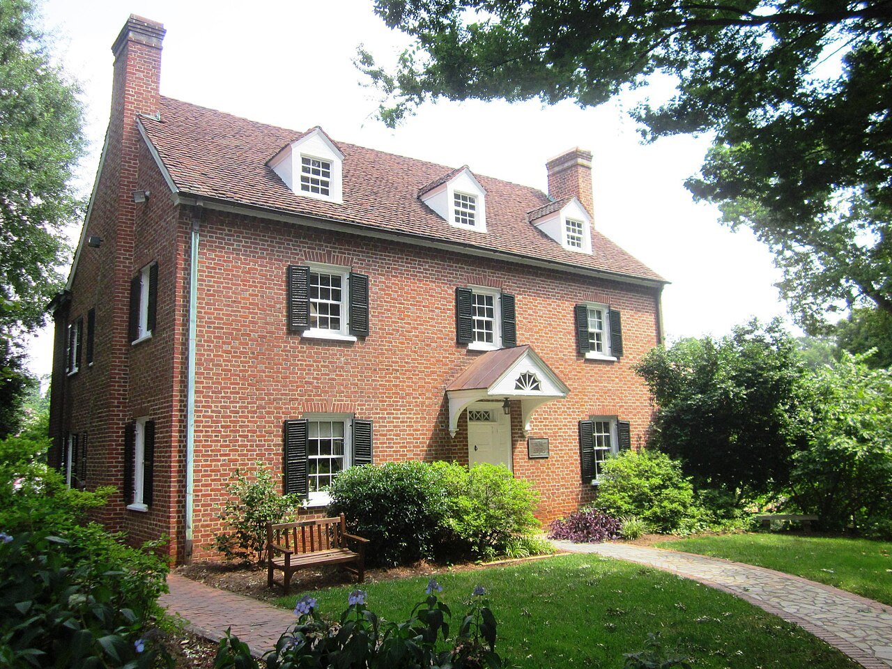 A brick house with dormers on the campus of Salem College.